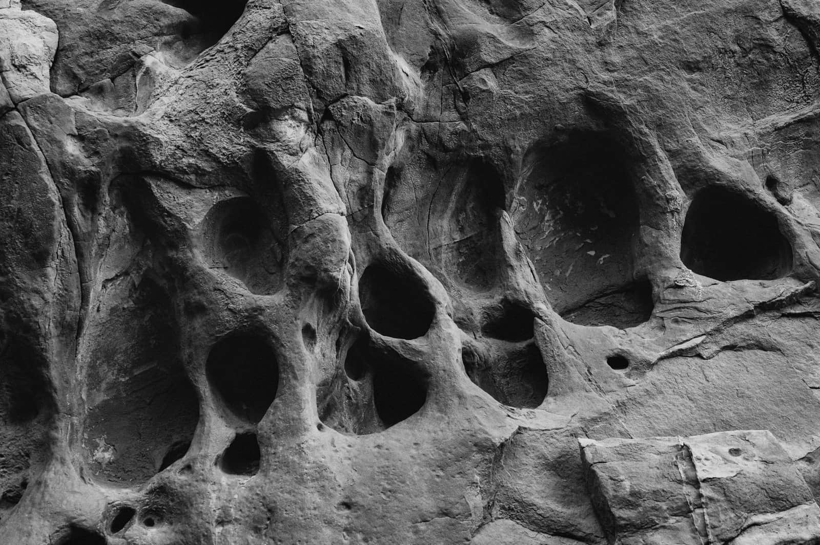 Black and white photo of a geological rock formation with distinctive holes and textures.